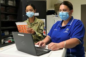 Australian Army officer Captain Chanel Aguilar (left) assists Ms Lisa Morgan conduct administration as part of Operation COVID-19 Assist.